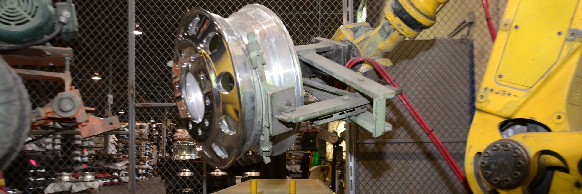 Robotic arm carrying heavy truck wheel to buffer