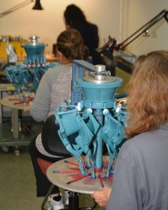 Employees assembling wax patterns onto an investment casting tree